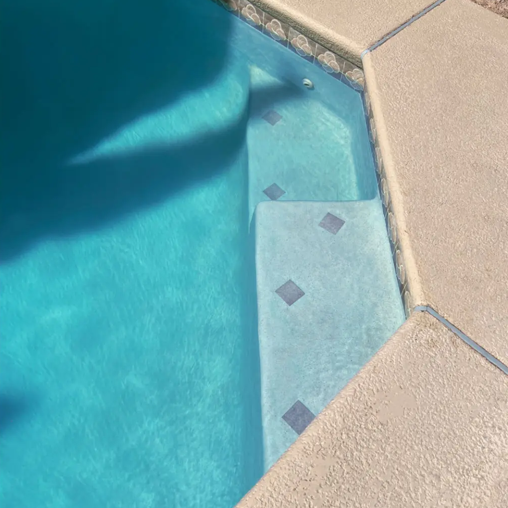 Sunlit pool steps in clear water